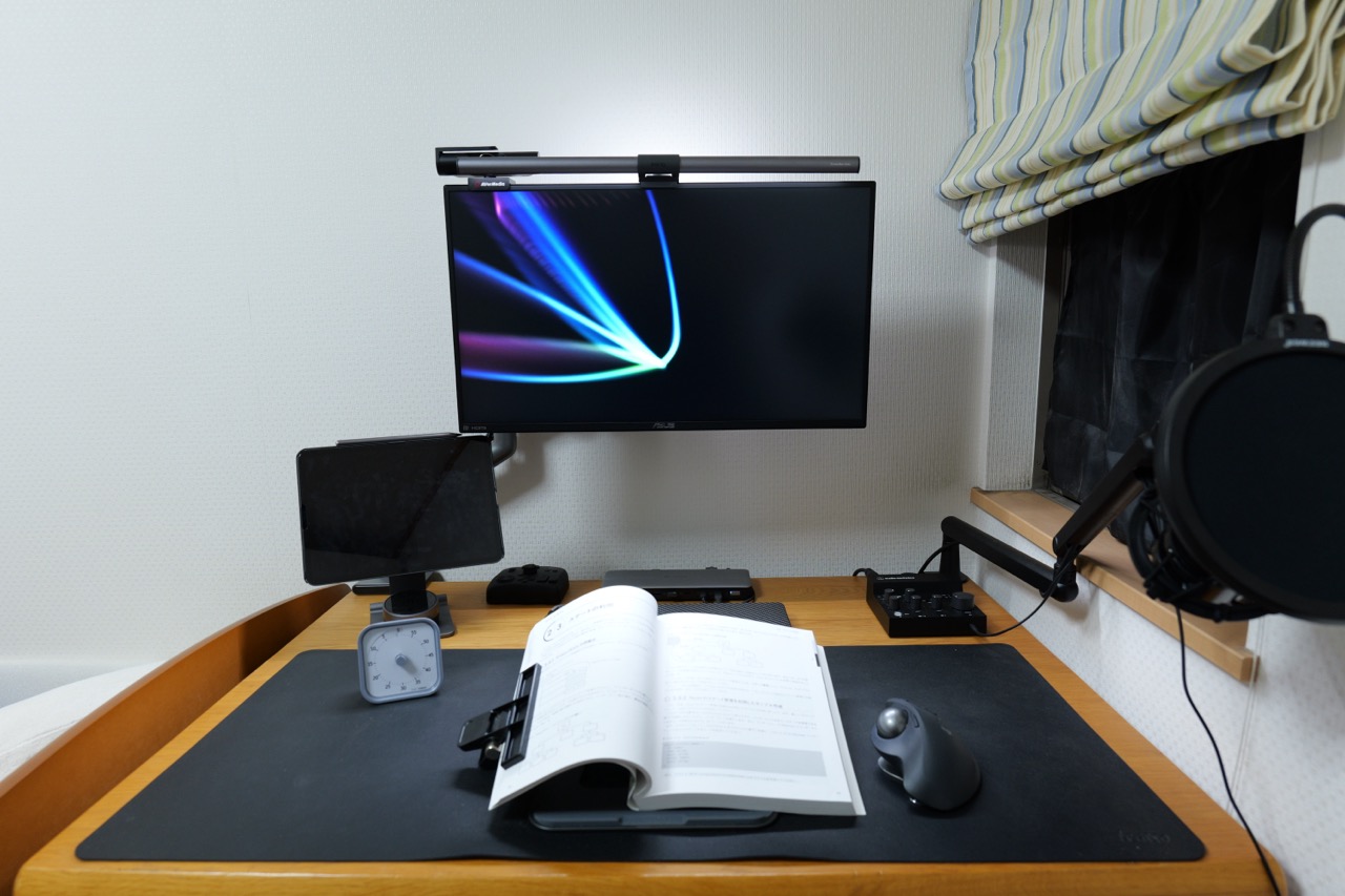 モニターライトを点灯したデスクで本を読んでいる写真